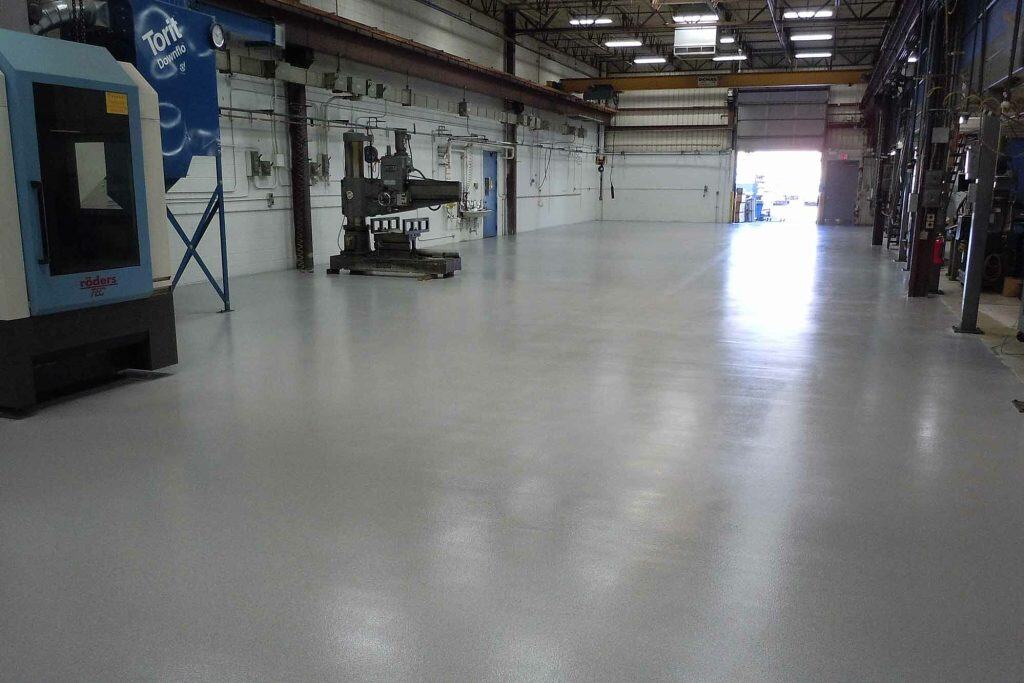 Wide industrial space with full-flake epoxy floor in light grey finish