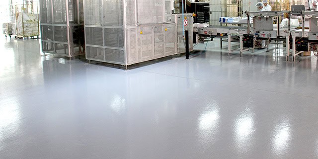 Professional applying epoxy coating on concrete floor with roller tool
